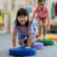 Two preschool-aged girls crawling over an indoor obstacle course to build motor skills through play.