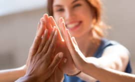 Group of women high five, while smiling and working together as a team.