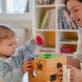 Educator in early learning classroom sitting at a table with a young girl as the two explore shapes and colors.