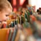 Toddler child peering into a display of children’s books, searching for a story to read.