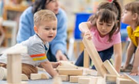Group of children in early learning classroom playing with wooden blocks – exploring early STEM concepts.