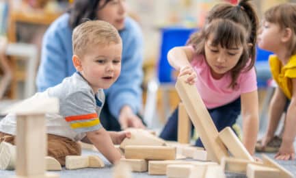 Group of children in early learning classroom playing with wooden blocks – exploring early STEM concepts.
