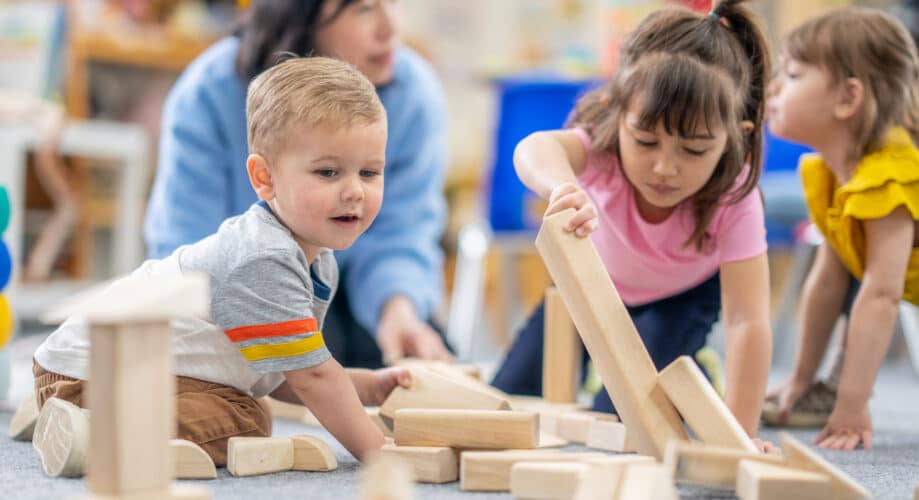 Group of children in early learning classroom playing with wooden blocks – exploring early STEM concepts.