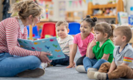 A teacher reads a picture book to a group of young children during circle time in an early learning classroom.