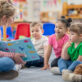 A teacher reads a picture book to a group of young children during circle time in an early learning classroom.