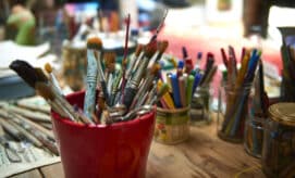 Paintbrushes and other art supplies for crafting sit on the table in an early learning classroom.