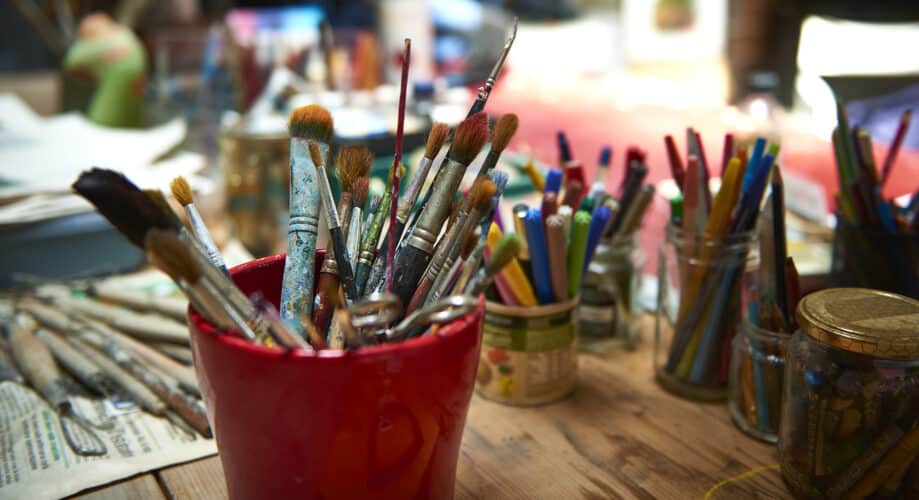 Paintbrushes and other art supplies for crafting sit on the table in an early learning classroom.
