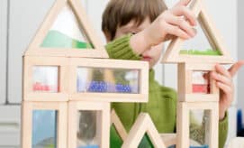Young boy stacks colorful blocks together, exploring STEM concepts in an early learning classroom.