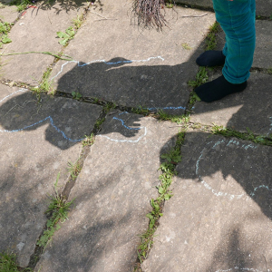 two Early Learners' shadows traced on the ground using chalk