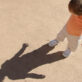 Toddler child plays outdoors and explores his shadow on a summer day.