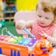 Toddler girl plays with xylophone, making music in an early learning classroom.