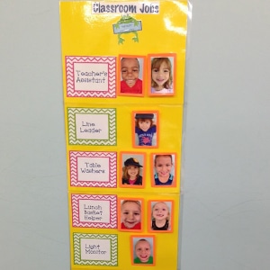 preschool classroom jobs chart made of yellow construction paper, laminated student pictures, and the designated classroom jobs to be assigned.