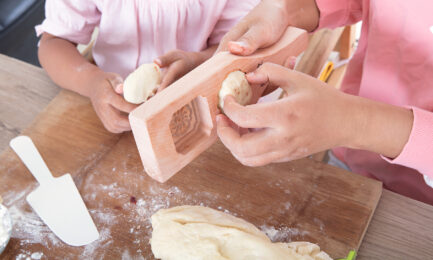 A young girl gets help forming dough into mooncakes for a Mid-Autumn celebration.