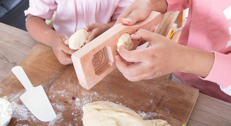 A young girl gets help forming dough into mooncakes for a Mid-Autumn celebration.
