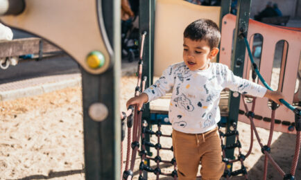 A young boy plays on outdoor play equipment.