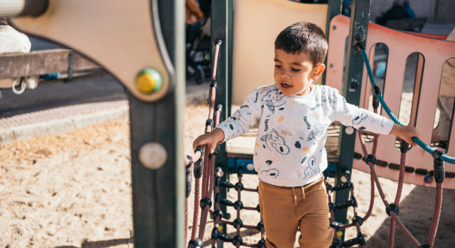 A young boy plays on outdoor play equipment.