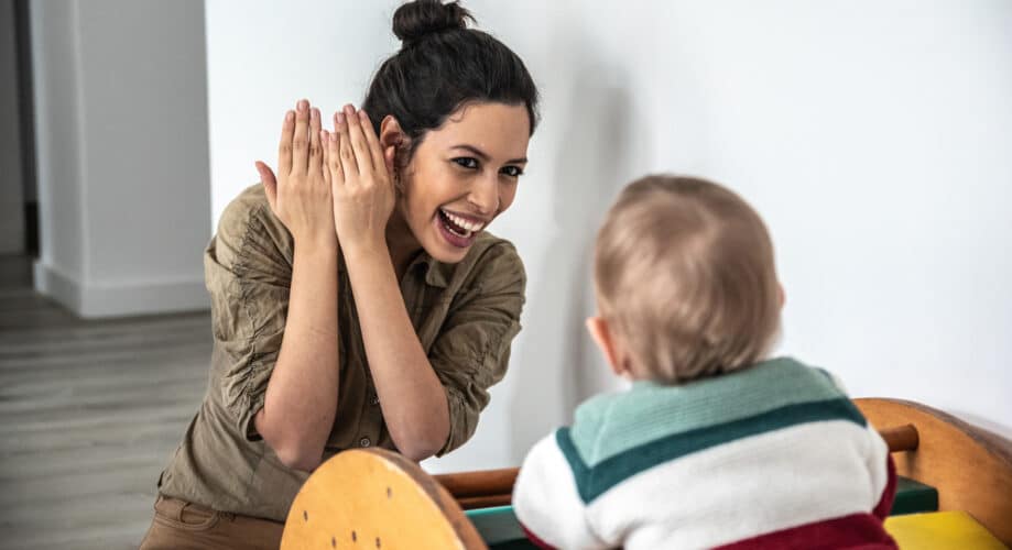 Caregiver and toddler play peek-a-boo together