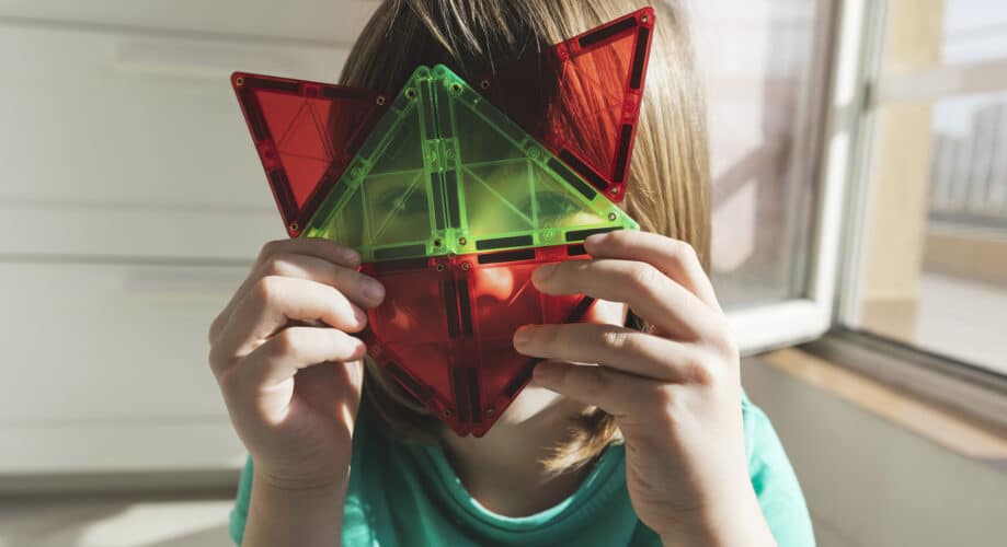 A child smiles while holding magnatiles.