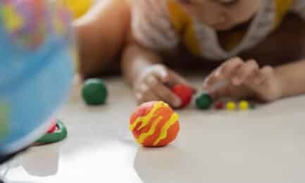 A young boy explores the planets with playdough and a globe.
