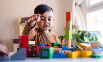 A toddler boy plays with blocks and wooden toys.