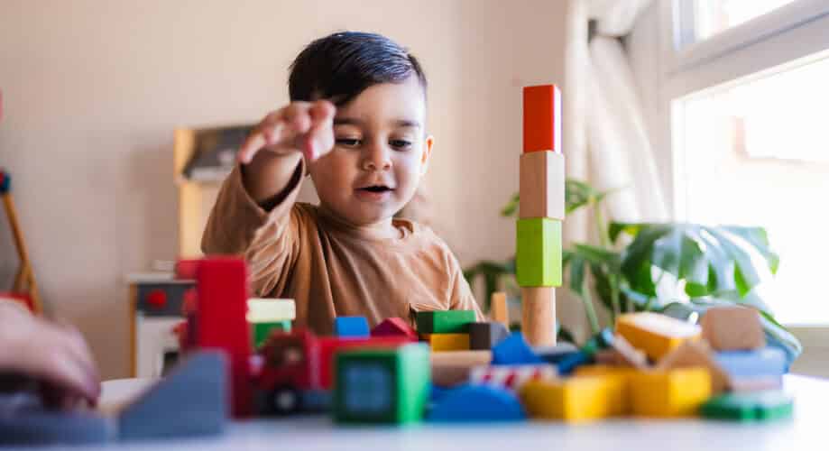 A toddler boy plays with blocks and wooden toys.