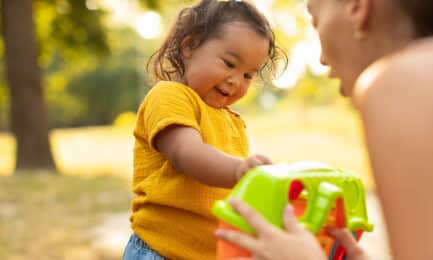 A toddler explores a toy with her caregiver.