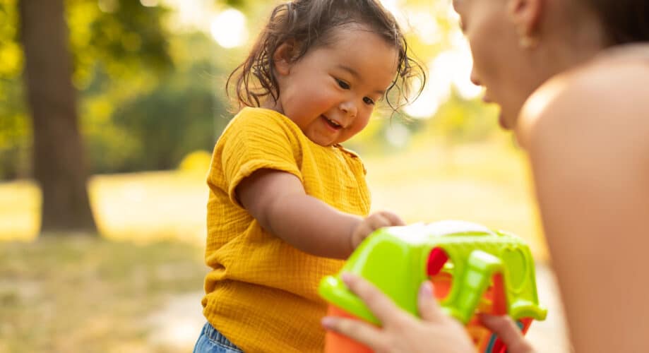 A toddler explores a toy with her caregiver.