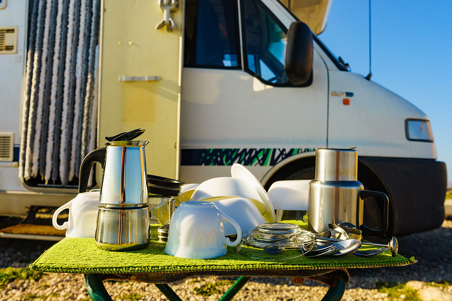  
											 Cups, plates, and coffee makers laying out to try in front of an RV
										  										 
