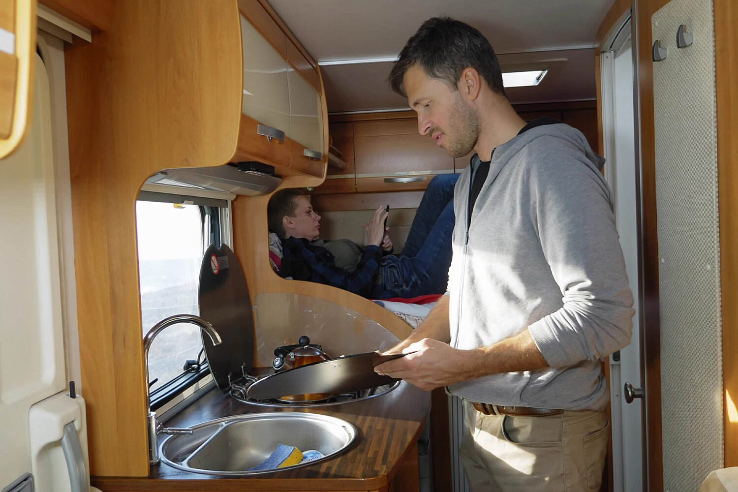  
											 A man washing dishes inside his RV
										  										 