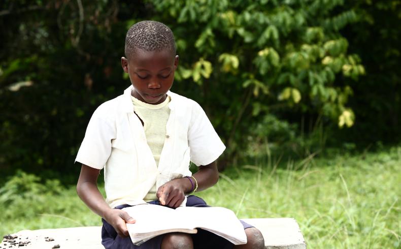A grade 2 student practising his reading skills in the school yard 5.JPG
