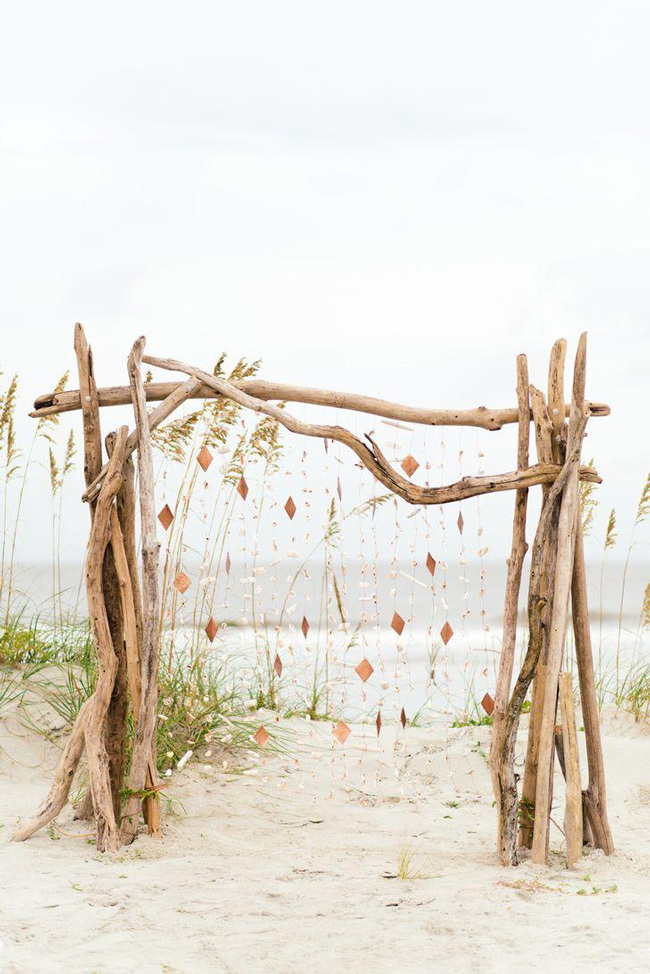 A modern driftwood beach ceremony arch with copper and seashells A modern driftwood beach ceremony arch with copper and seashells