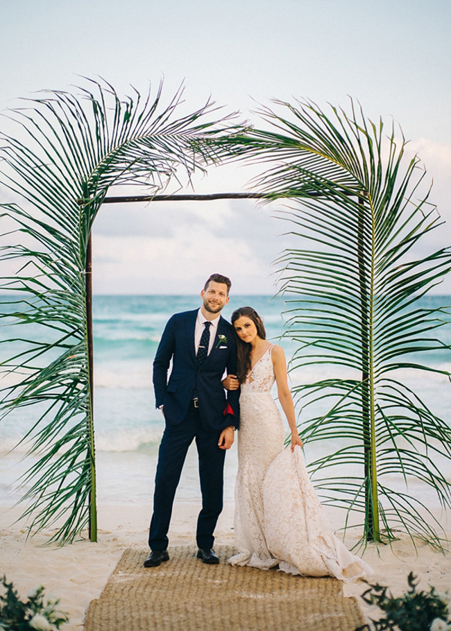 Palm fronds surround a beach wedding ceremony arch Palm fronds surround a beach wedding ceremony arch