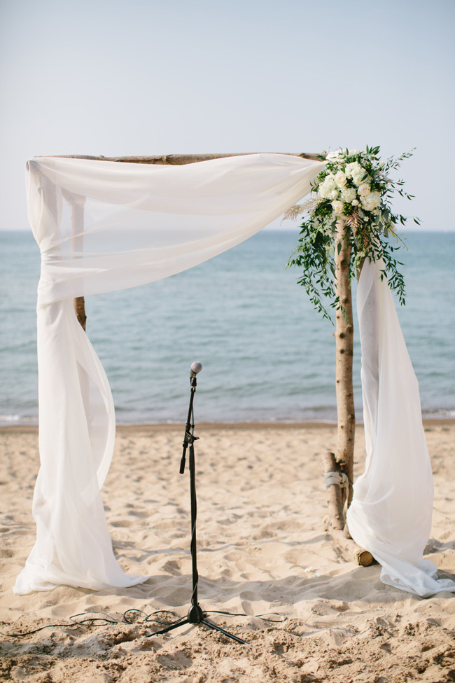 Birch wedding ceremony arch on the beach with white chiffon Birch wedding ceremony arch on the beach with white chiffon
