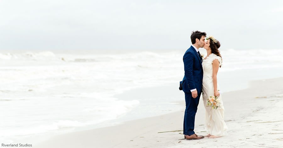 6 Ideas for Beach Wedding Décor Newlyweds kiss on the beach in front of the ocean