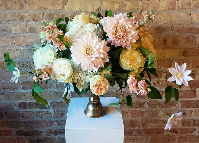 Ways to give back when planning a wedding A floral centerpiece with pale pink peonies by Pollen Chicago