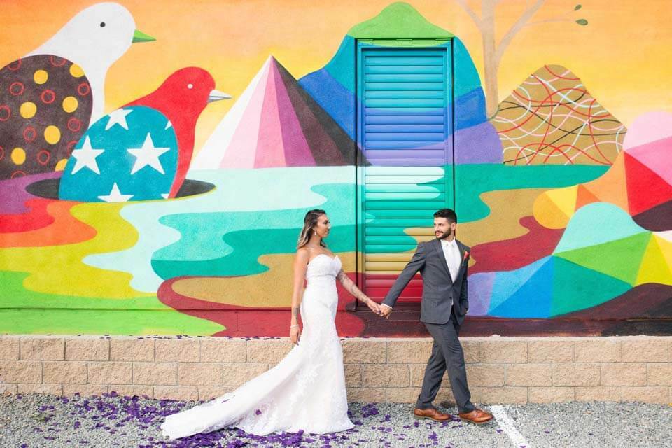 Newlyweds post in front of a colorful mural for wedding photos