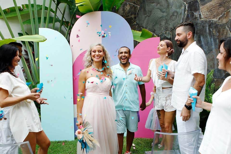 Bride and groom smile in front of a colorful, contemporary-shaped wedding ceremony backdrop