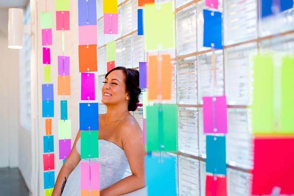 Bride smiles through colorful paper banners hung from the reception ceiling