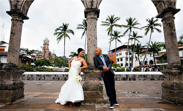 A bride and groom lean against ruins in an exotic destination