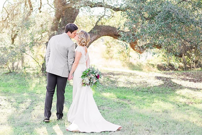 Everything you need to know about having your wedding in Dripping Springs, TX Newlyweds kiss in a beautiful shady grove in Dripping Springs Texas