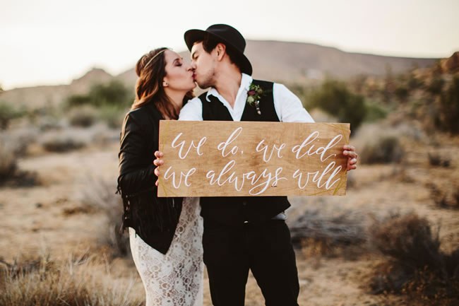 Boho couple with beautifully calligraphed elopement sign