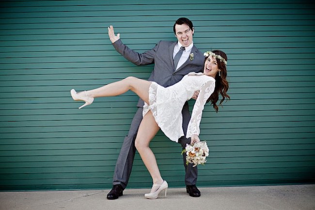 Groom dipping his bride in front of a bright teal wall