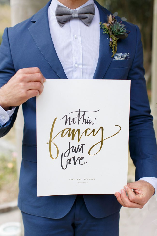 Groom holding a 'Nothing Fancy, Just Love' sign