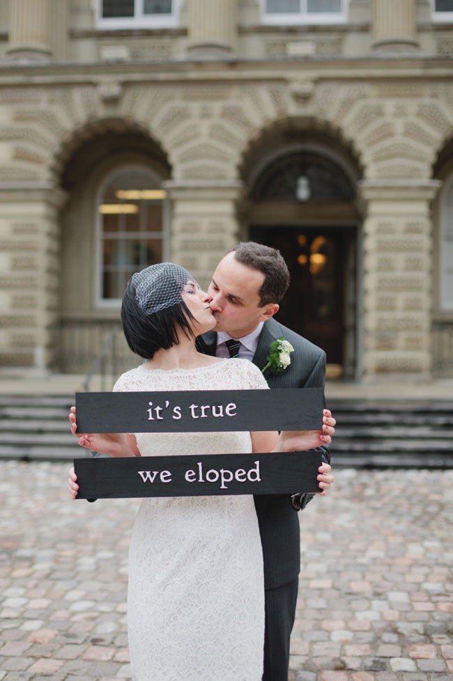 Newlyweds with an 'It's True, We Eloped' sign