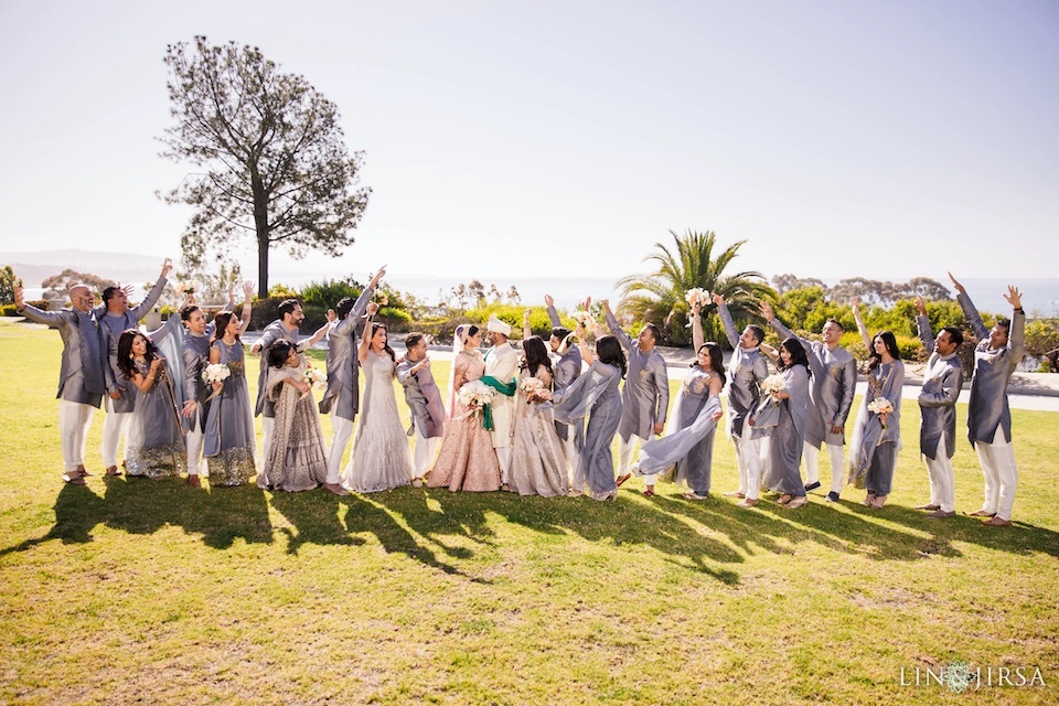 Large Indian wedding party cheers for the newlywed bride and groom