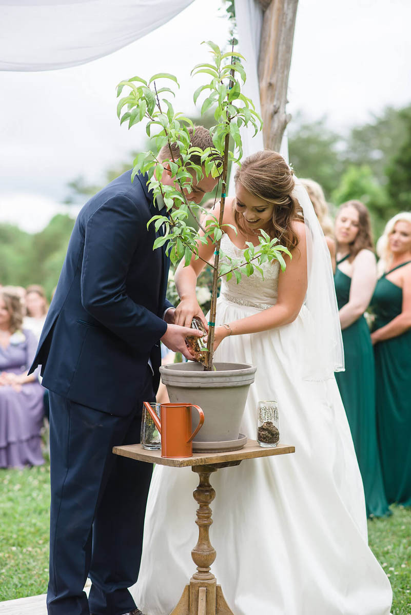 A bride and groom plant a tree together during their wedding ceremony