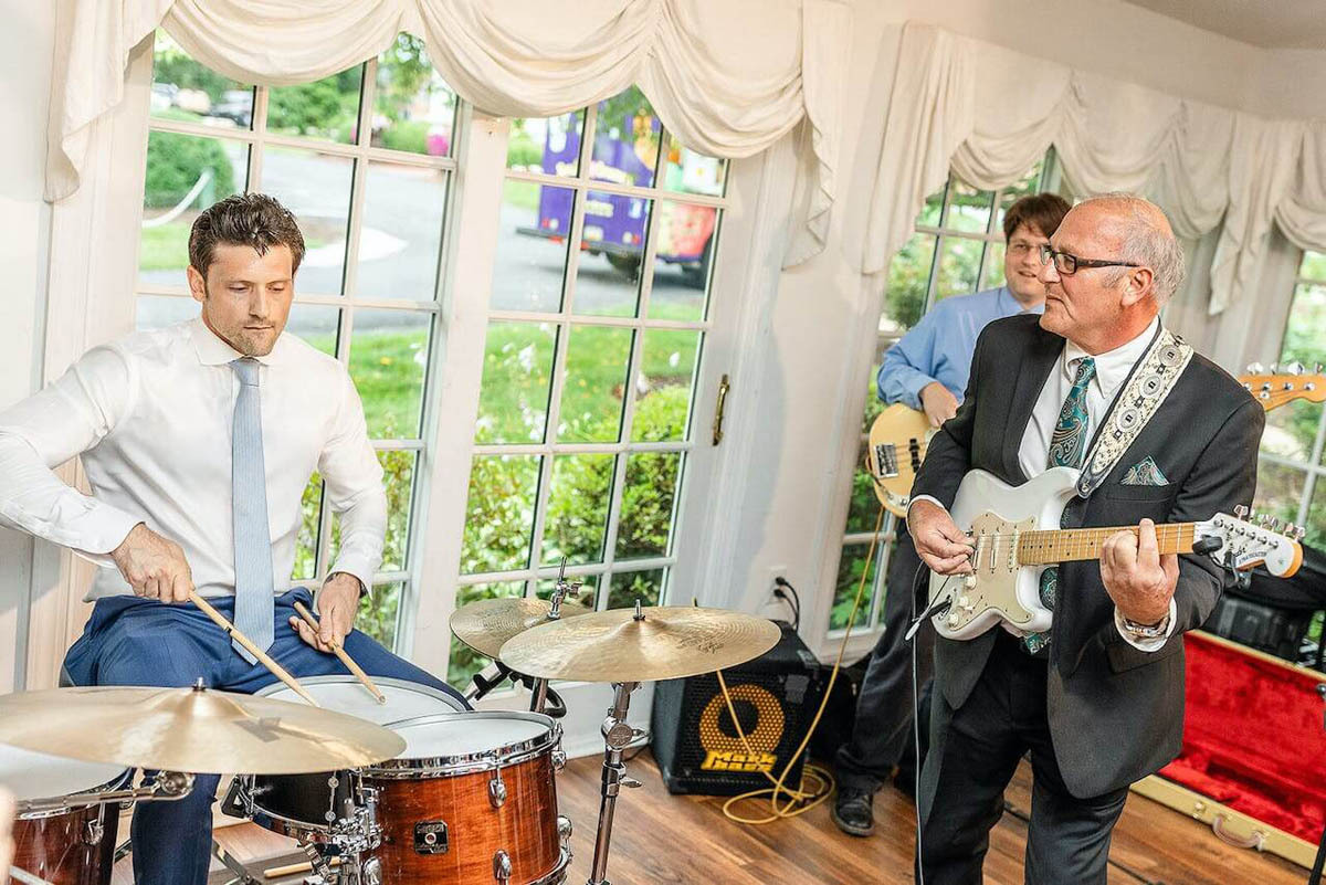 A groom and his father play music together at the reception