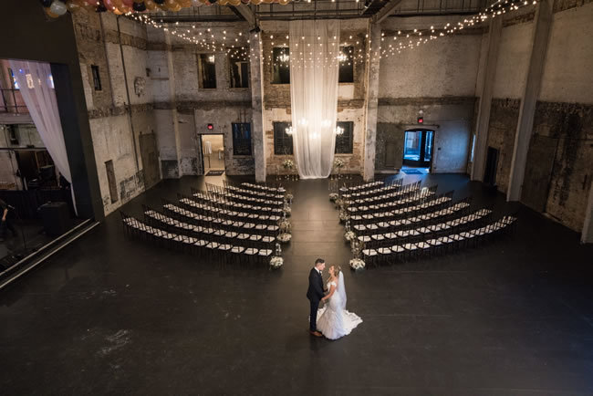 Bride and groom kiss in front of minimalist industrial-wedding ceremony