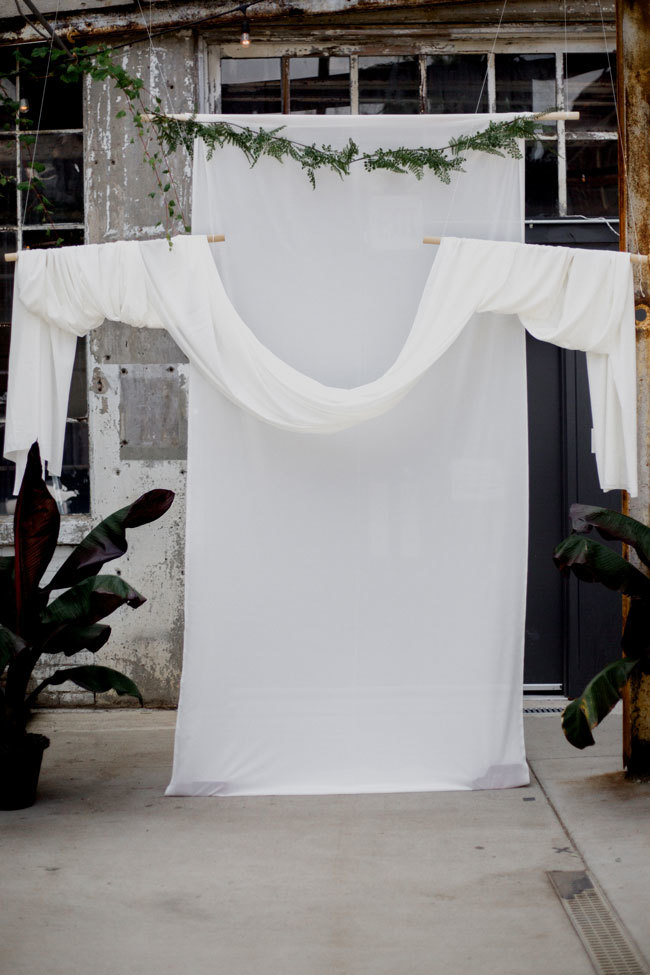 White draping for the ceremony backdrop at an industrial-chic wedding White draping for the ceremony backdrop at an industrial-chic wedding