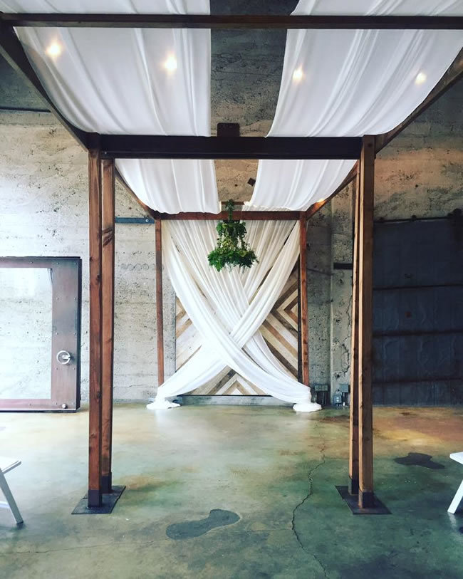 Luce Loft industrial wedding ceremony arbor with white draping Luce Loft industrial wedding ceremony arbor with white draping